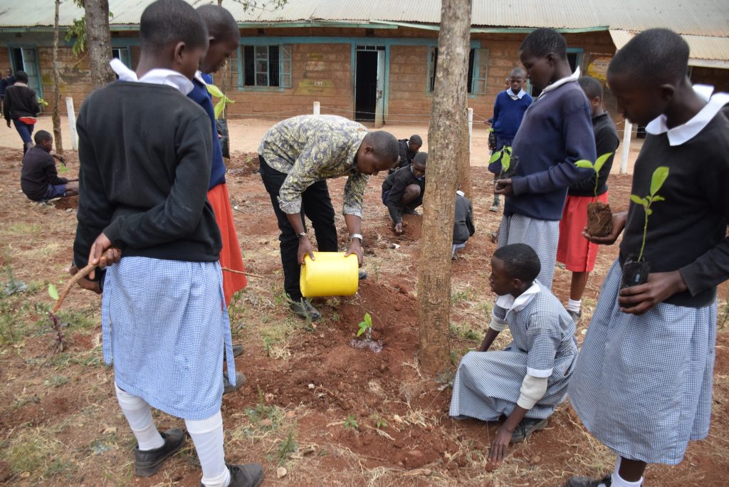 John, an AVSI field officer demonstrating during a tree planting activity at Nkaimurunya Primary school in Kajiado County.