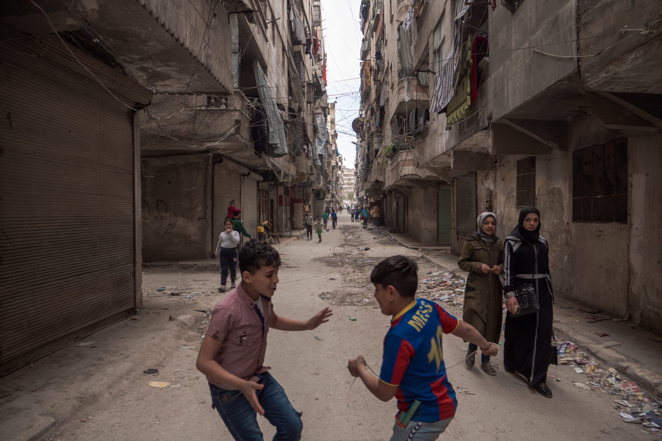 Due bambini si rincorrono in una strada del quartiere di Ansari Al-Sharqi Siria