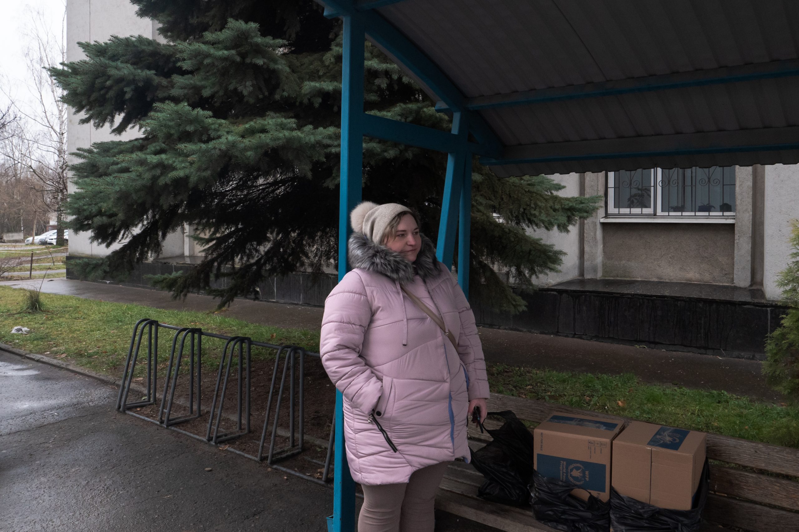 Tatiana davanti a una delle sedi del comune di Sumy. Aspetta un conoscente che l’aiuterà a trasportare due pacchi di aiuti alimentari